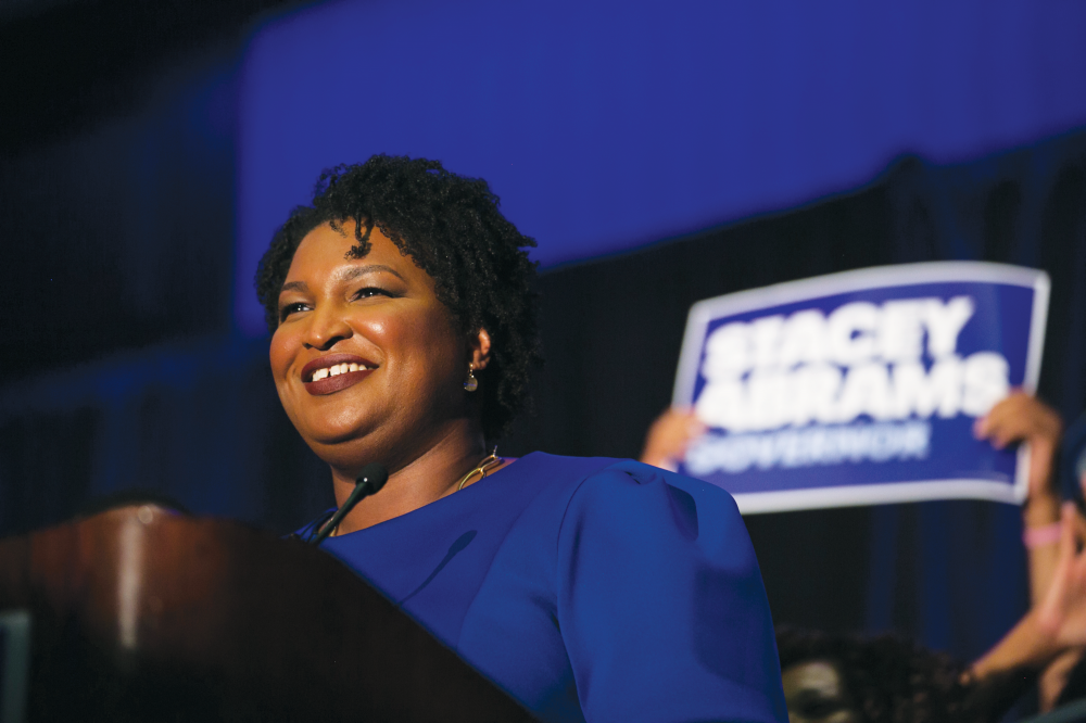 Woman standing in front of a sign that says Stacey Abrams