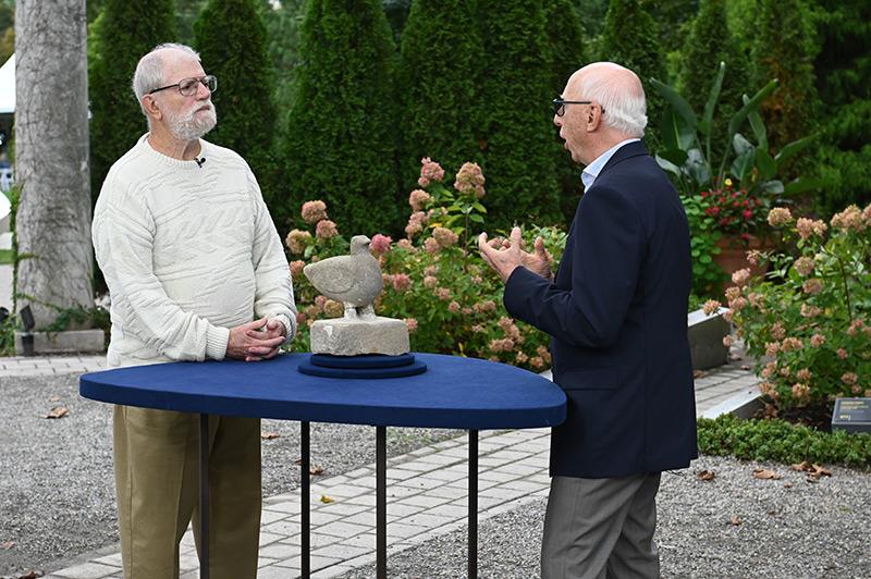 two men looking at a sculpture outside image