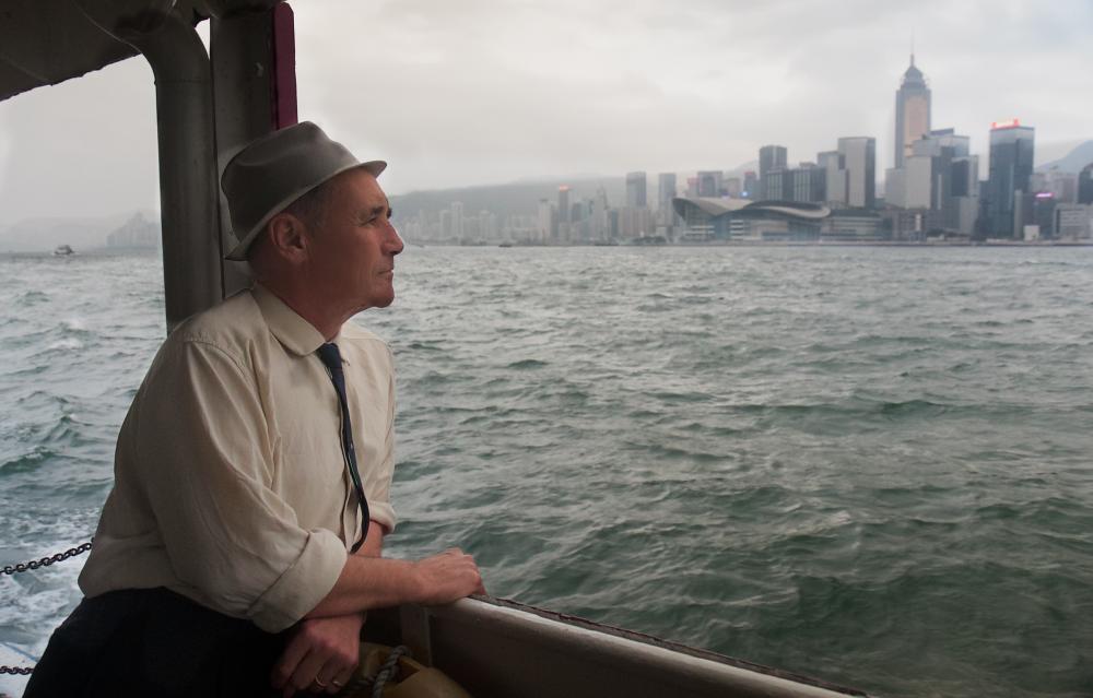A man on a ferry looking out at a city
