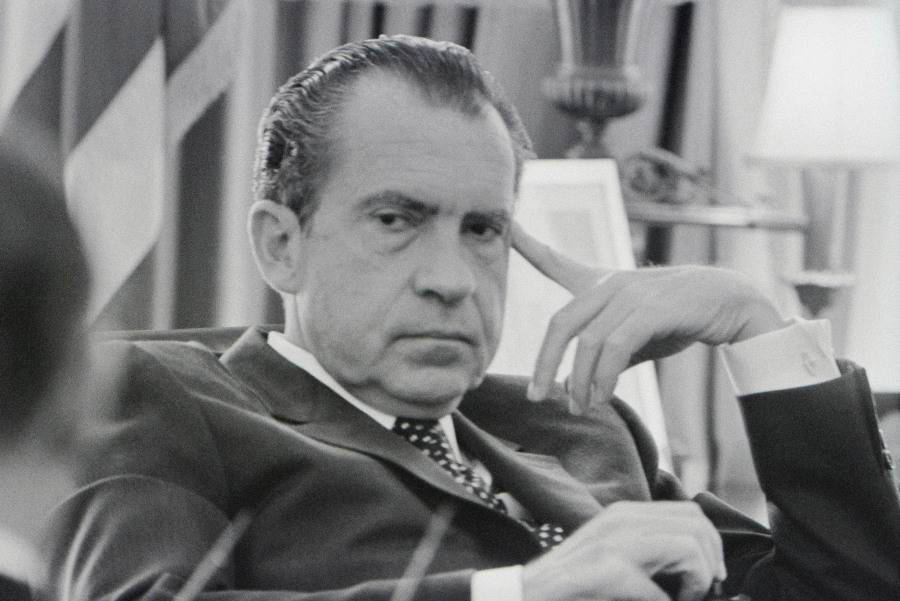 Black and white image of President Richard Nixon with his pointer finger to to temple image