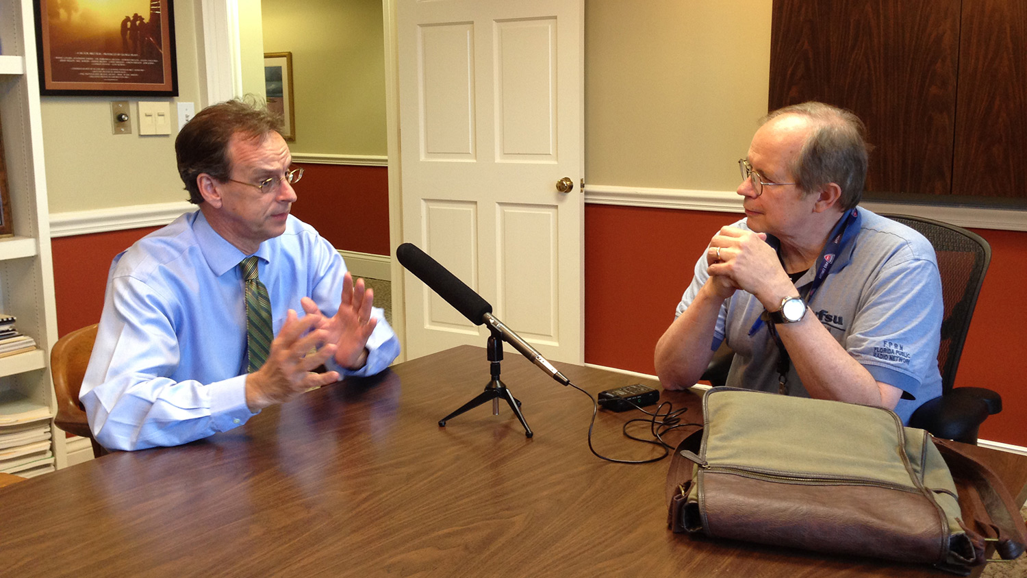 two men talking at table with microphone