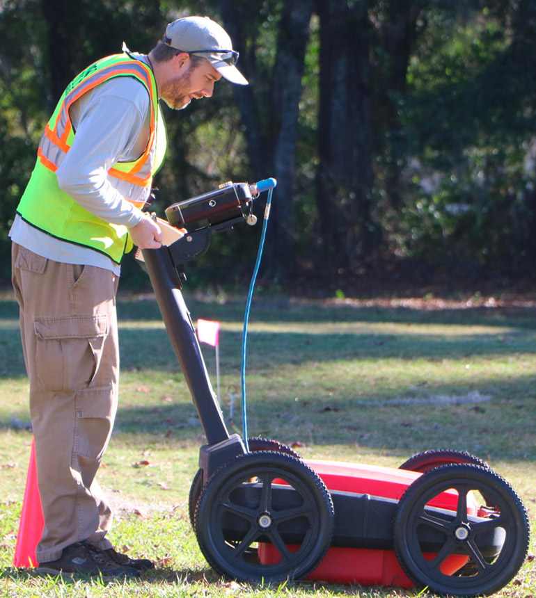 A man with a red Ground Penetrating Radar device