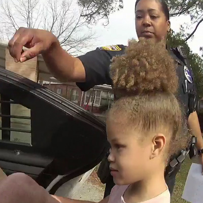 police officer escorting little girl into police car