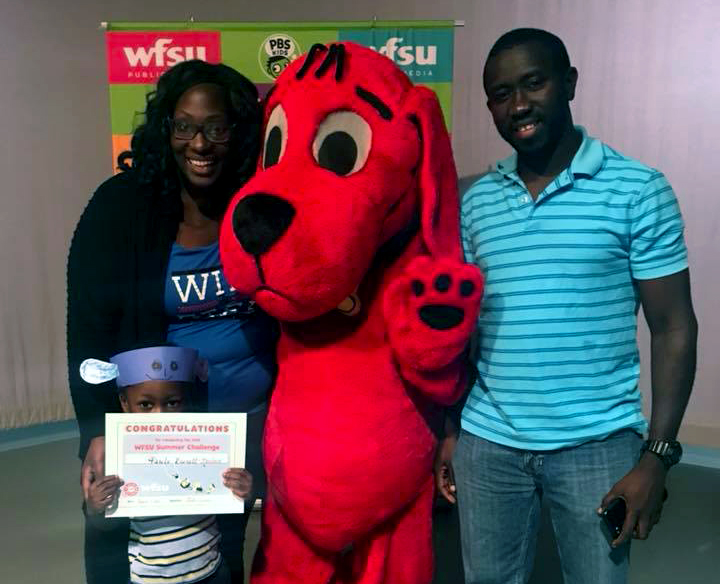 family standing with clifford the big red dog, child holding summer challenge certificate of completion