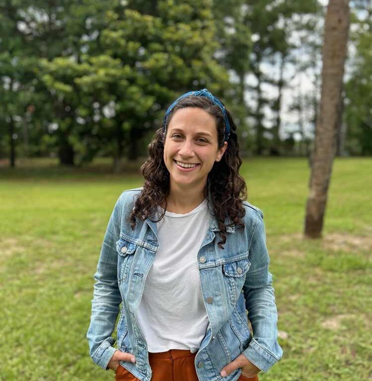 woman in white shirt and jean jacket, smiling