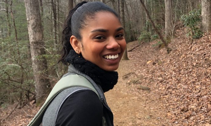 Bradi stewart pictured walking in the woods during a overcast fall day.