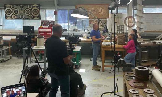 A camera crew is set up in the FSU MagLab with a reporter interviewing individuals at a lab station.