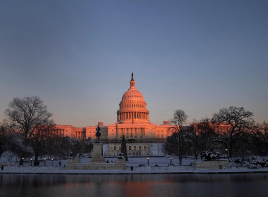 Image of the united states capitol building during the sunrise in the winter over the capital reflecting pool.