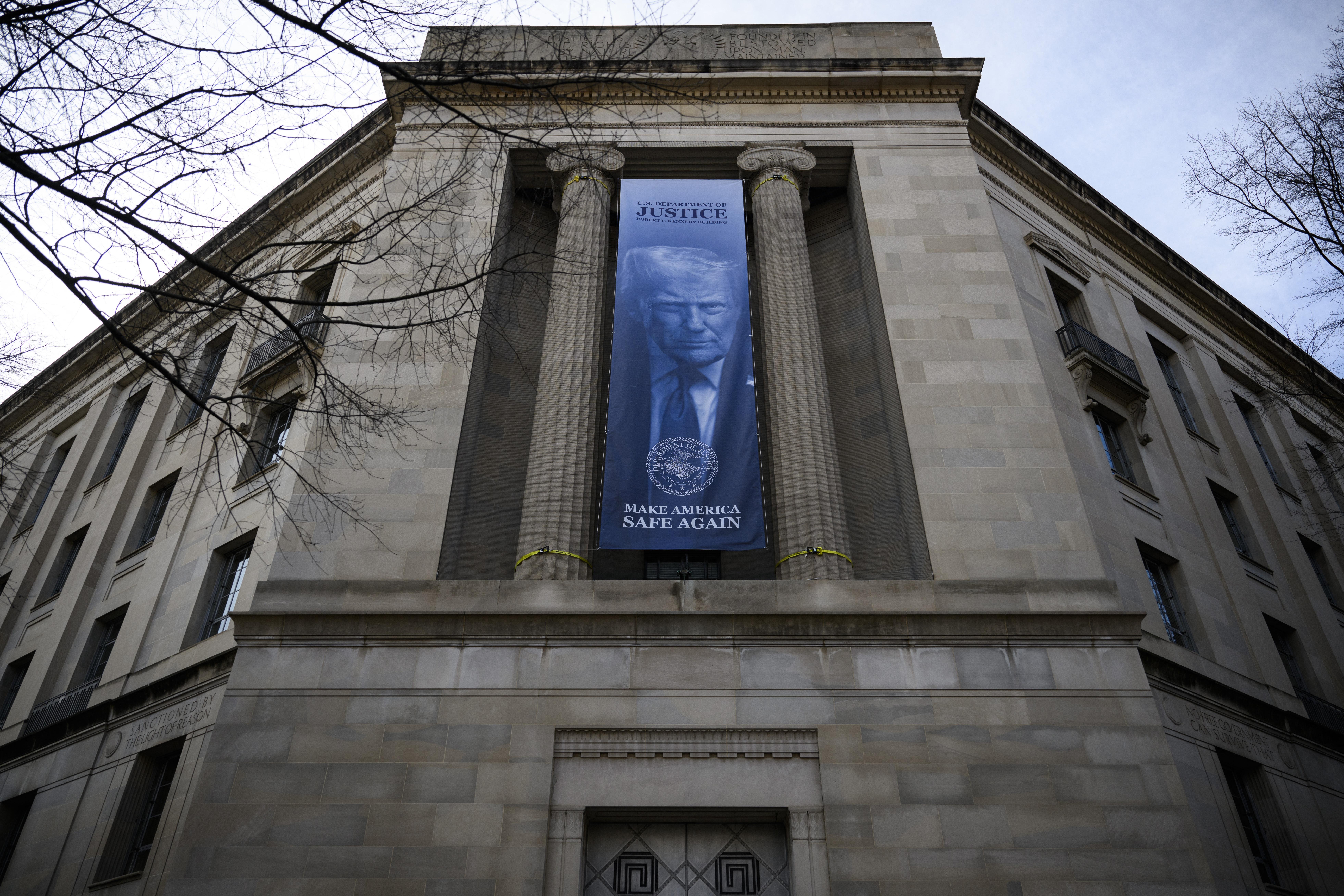A banner featuring an image of President Trump is displayed on the facade of the Department of Justice headquarters in Washington, DC. The Justice Department has been trying to force states to hand over sensitive voter data that it plans to share with the Department of Homeland Security.
