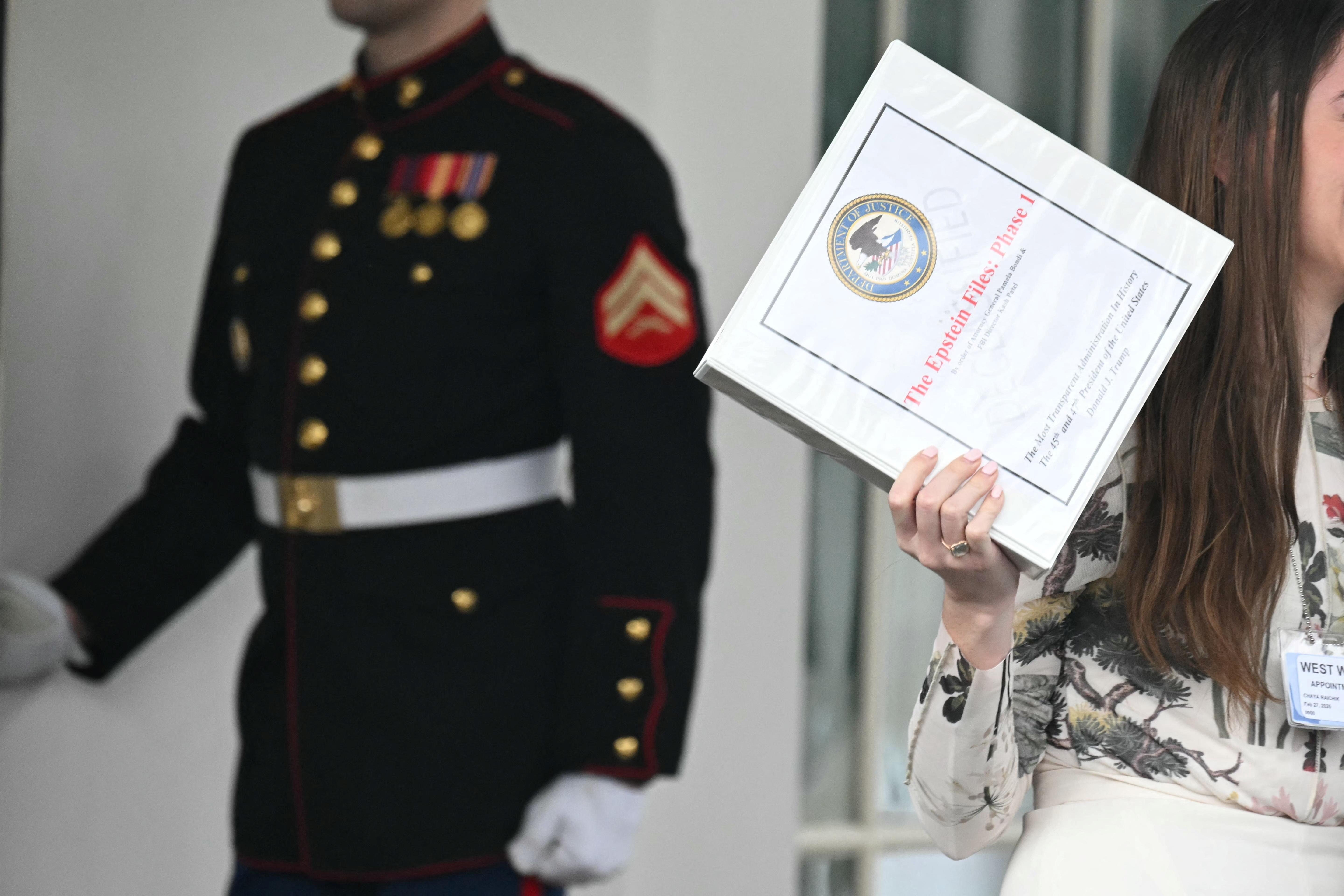 Unidentified people carrying binders bearing the seal of the US Justice Department reading 