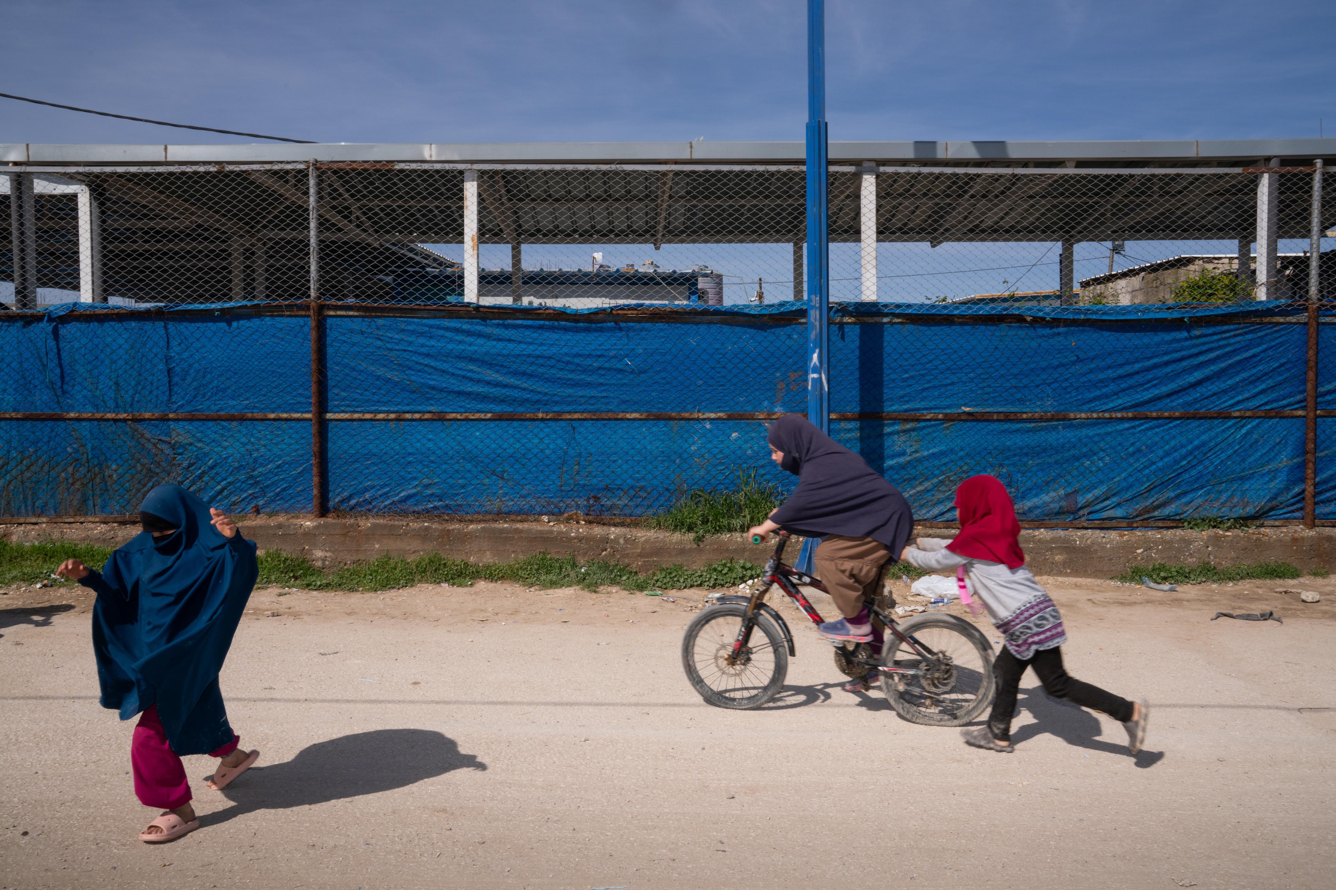 Children ride a bicycle and play in the Roj camp in a Kurdish-held territory in northeast Syria in March. The detention camp houses wives and children of ISIS members.