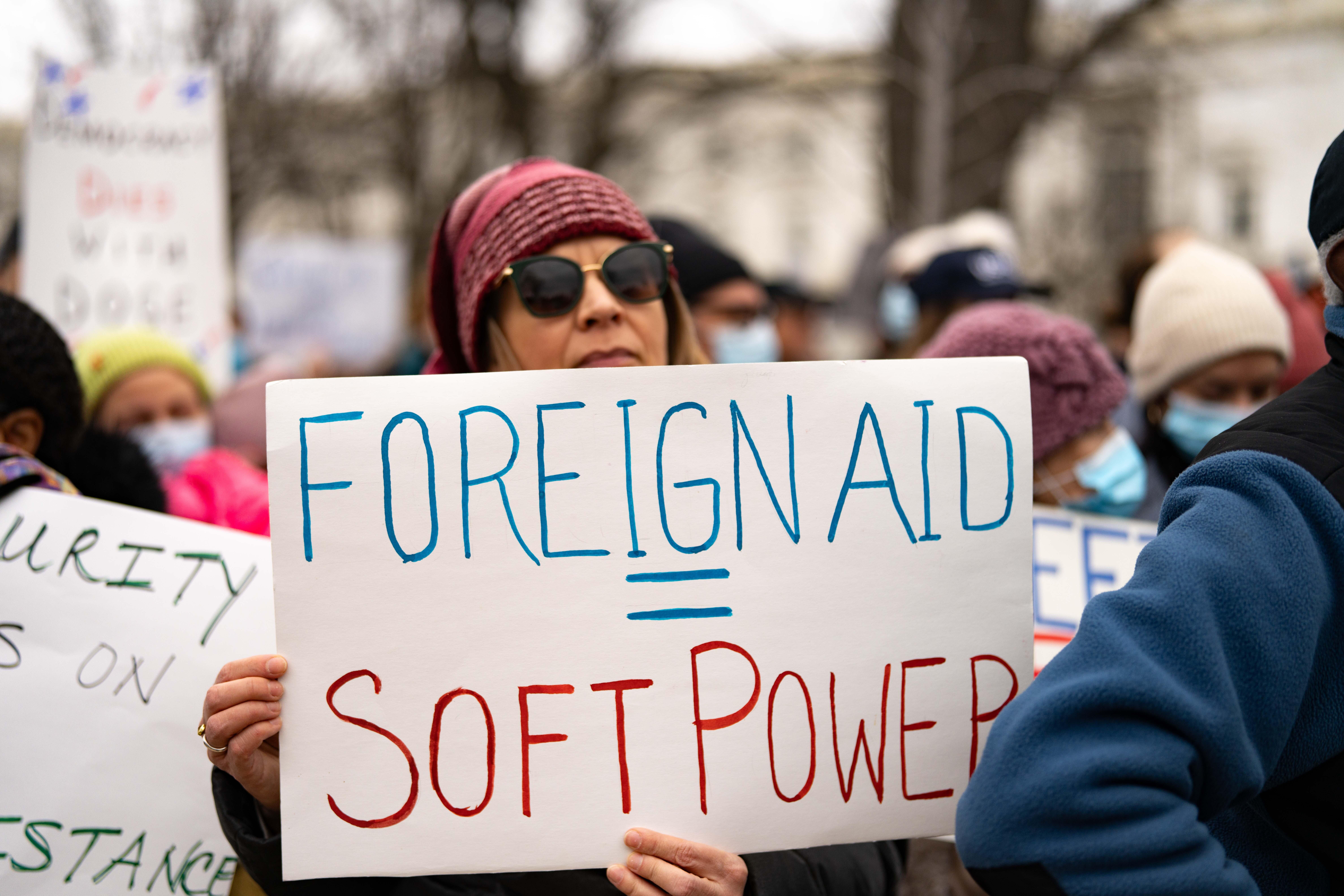 A protester carries a sign that equates foreign aid with soft power during a rally near the U.S. Capitol to protest the dismantling of USAID, the international agency charged with dispensing humanitarian aid around the world on behalf of the United States.