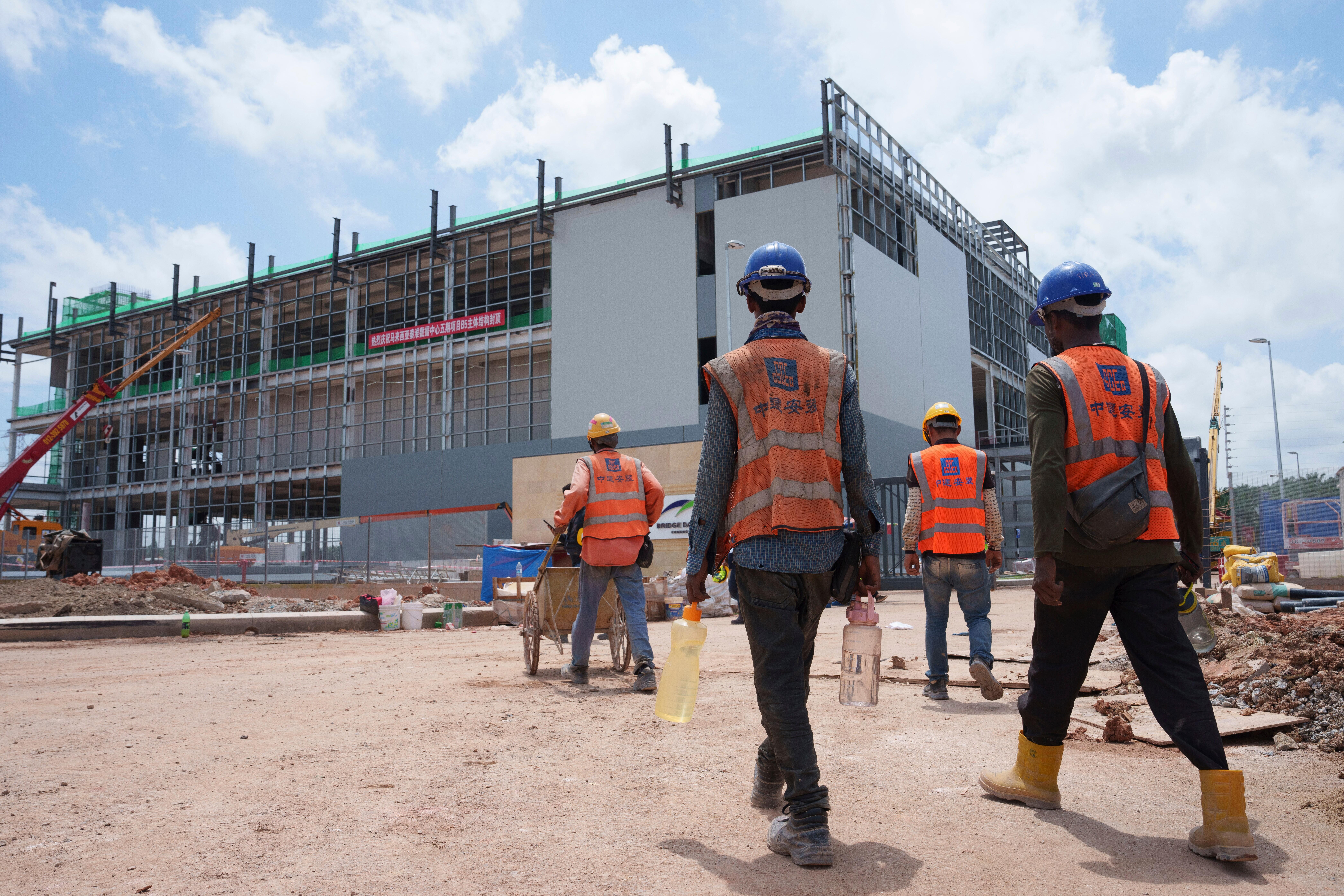 FILE -Construction workers walk to a data center building under construction in Sedenak Tech Park in Johor state of Malaysia, Sept. 27, 2024.