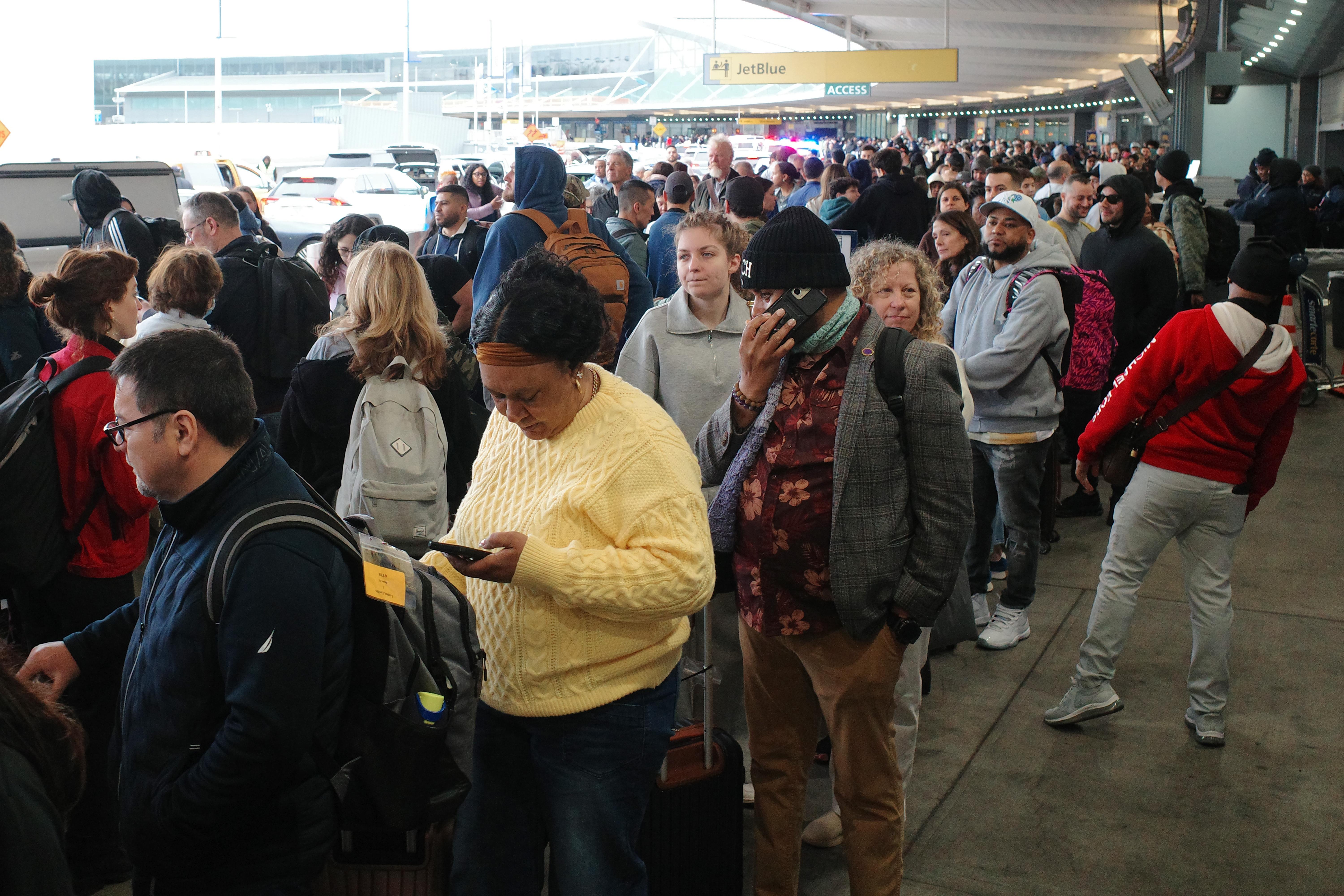 Travelers wait in line to go through TSA screening in Terminal 5 at John F. Kennedy International Airport on Friday in New York. The partial government shutdown has brought the longest TSA wait times in history, forcing some airline customers to rebook flights missed due to airport delays.