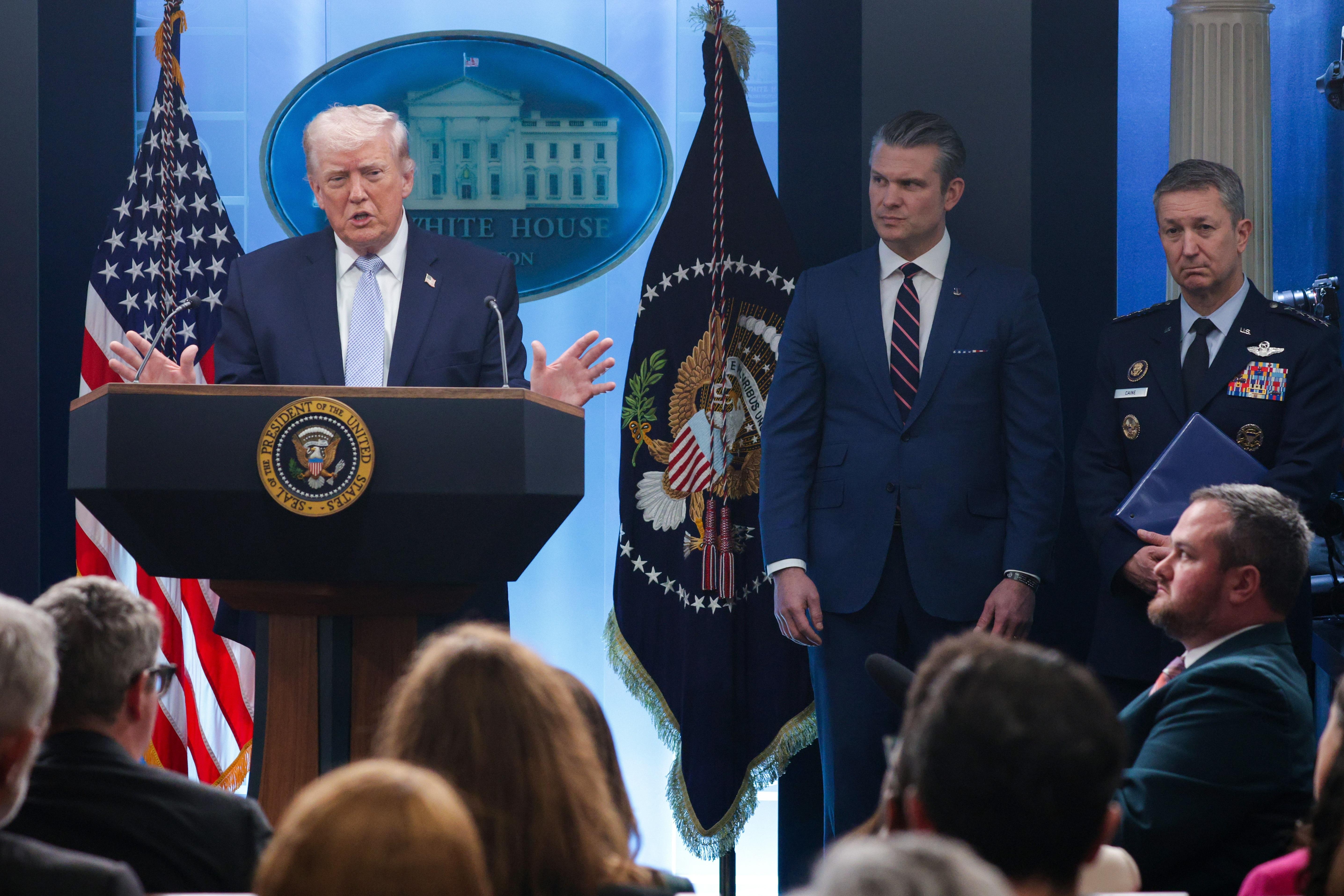 President Trump speaks as Secretary of Defense Pete Hegseth (center) and the chairman of the Joint Chiefs of Staff, Gen. Dan Caine, look on during a news conference at the White House on April 6.