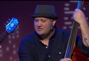 The New 76ers Perform “Gone” A man passionately playing music on his instrument with strings