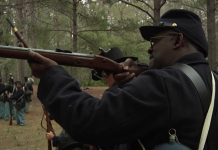 Reenacting History at the Battle of Natural Bridge Man dressed in colonial America attires aims and prepares to shoot gun