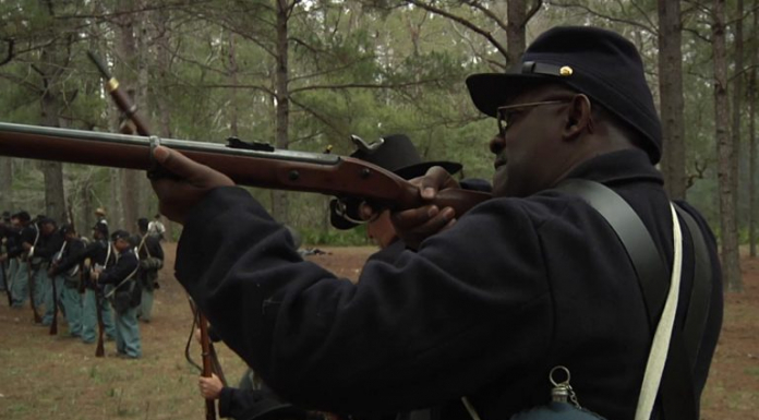 Reenacting History at the Battle of Natural Bridge Man dressed in colonial America attires aims and prepares to shoot gun