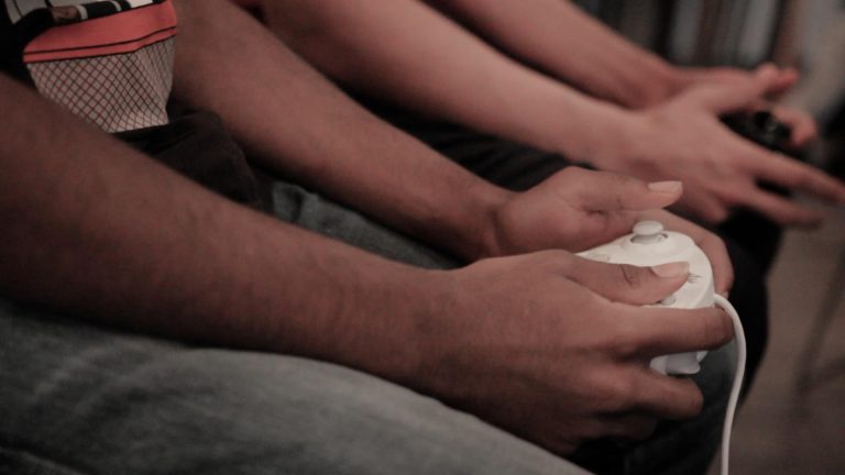 Gamers Unite to "Smash" Gamers hold controllers in their hands as they play one another