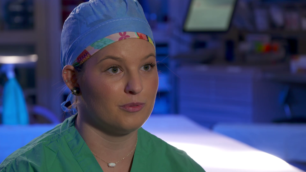 Woman in green scrubs and blue hat