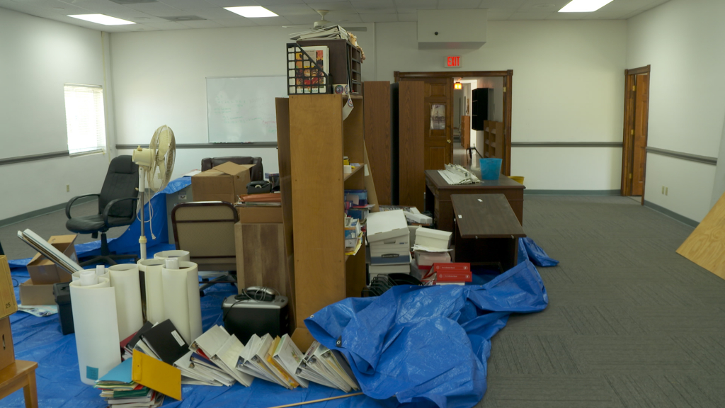 Large meeting room with funiture piled up in the middle of the space.