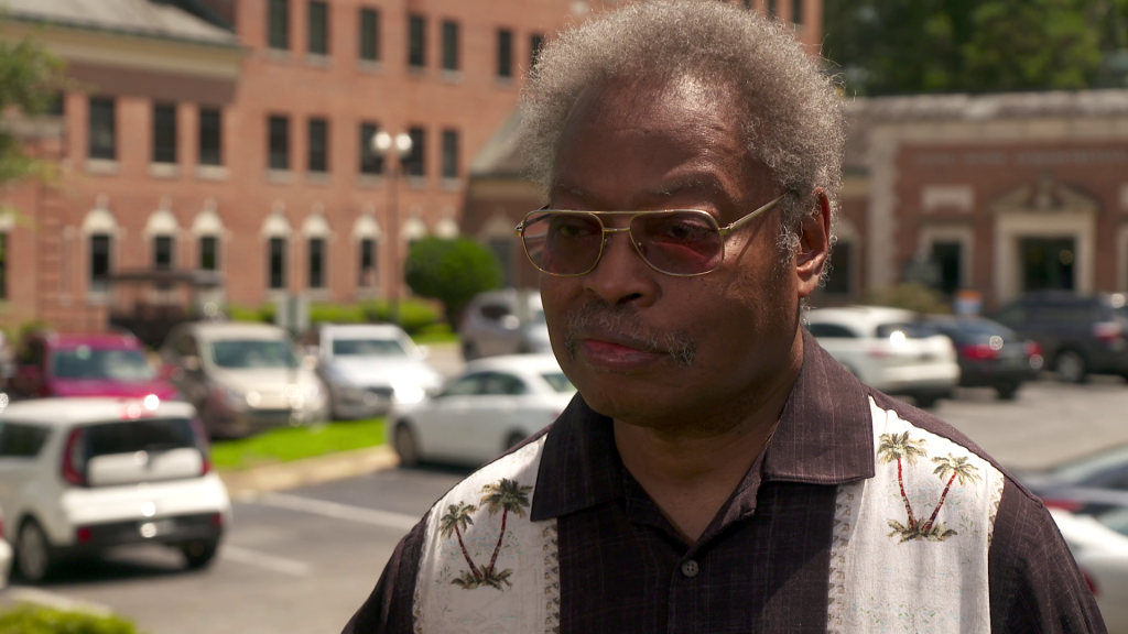 A man wearing sunglasses and standing in a parking lot