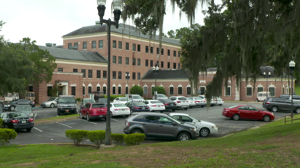 Large brick building with modern day cars in front of it.