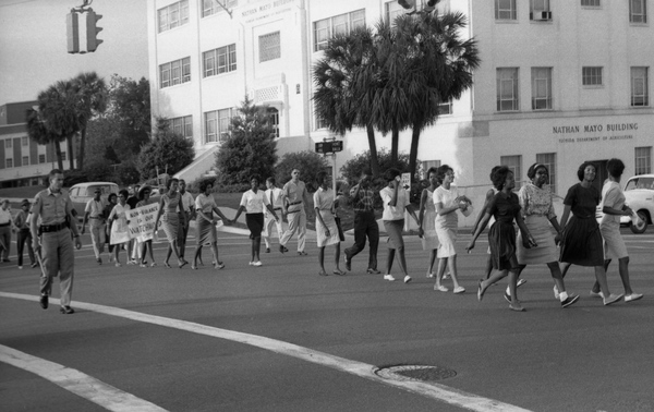 A group of people crossing a street in front of a building