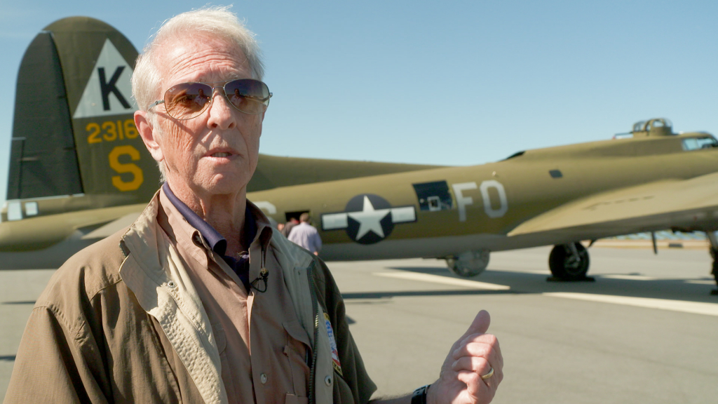 A man wearing a suit and tie standing next to a plane