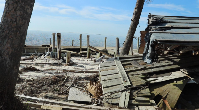 Sea Level Rise on the US 98 and Saint Vincent Island A wooden bench sitting next to a body of water