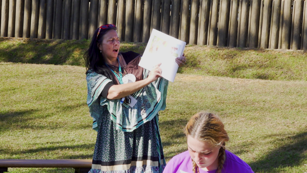 A woman showing the page of a book and young woman in front of her.