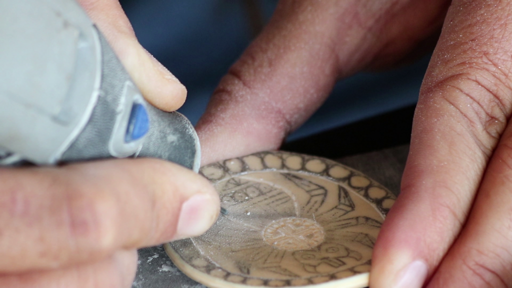 A close up of a hand carving a shell