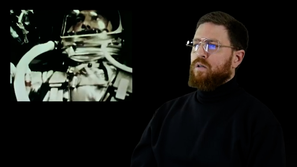 A man wearing glasses taking a selfie in a dark room