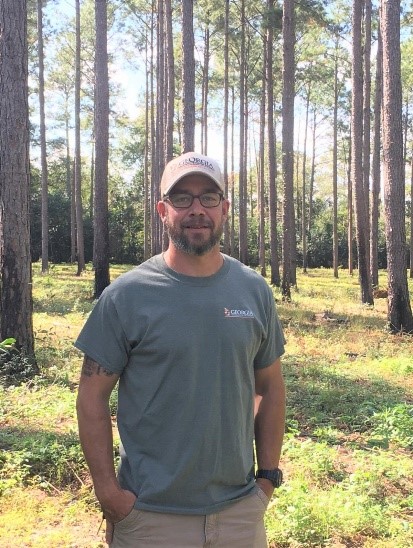 A man standing in front of a forest