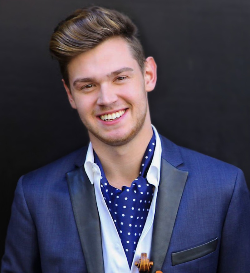 A person wearing a suit and tie smiling at the camera
