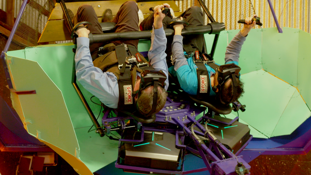 Two people inverted on a motion platform.