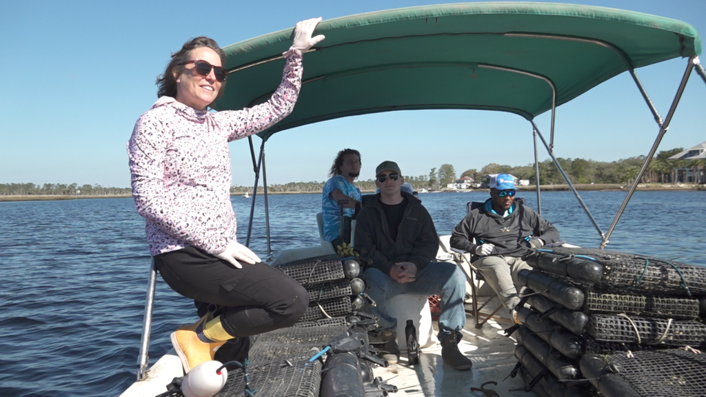 A woman and three men on a boat in a body of water.