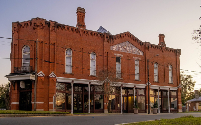 A large brick building with a clock on the side of a road