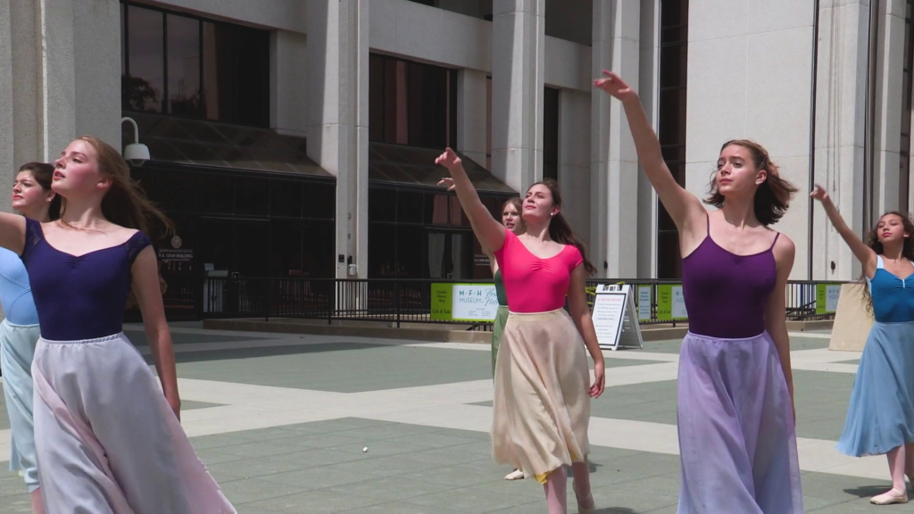 Severald danceers with extened right arms standing in front of the RA Gray Building in Tallahassee.