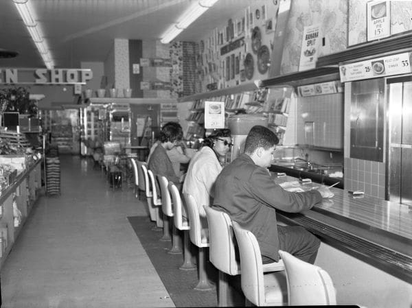 Several people sitting at lunch counter in black and white photo