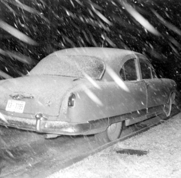 snow falls on a vintage car