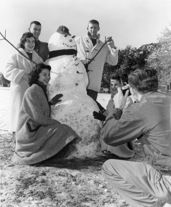 A group of people posing for a photo with a snowman