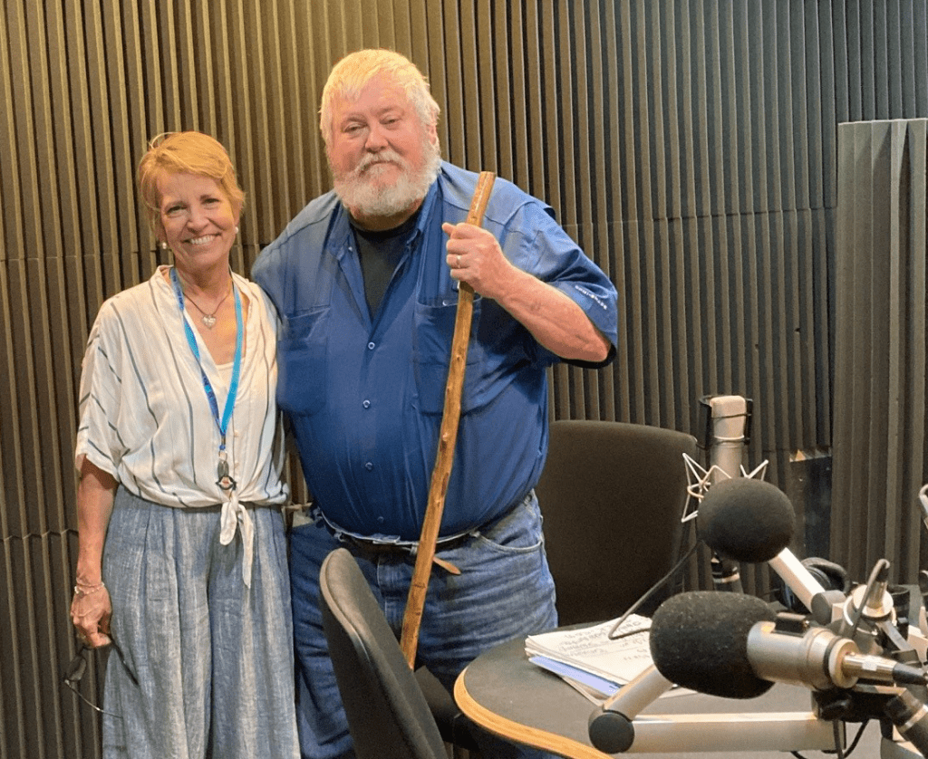 A woman and a man posing for a picture with microphones.