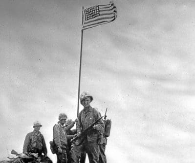 A group of soldiers in front of an American flag.