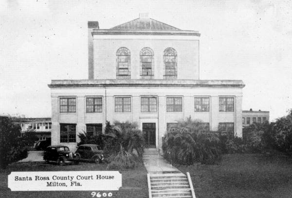 A vintage photo of an old building. placard on it says "Santa Rosa County Court House Milton, Fla."