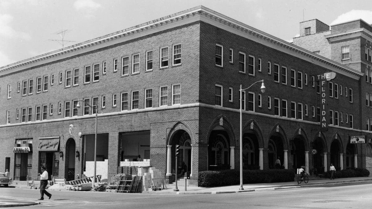 A black and white photo of three story hotel with the sign The Floridan on the side.
