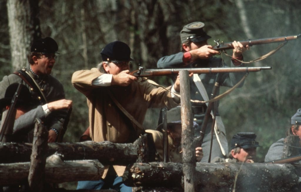 Reenactors dressed up in Civil War Confederate uniforms firing guns