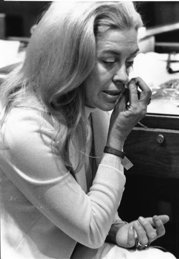 Black and white photo of a woman with a tissue wiping her eye.