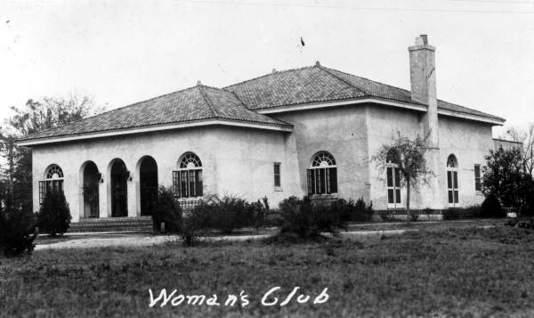 A vintage photo of an old building with the words Woman's Club underneath
