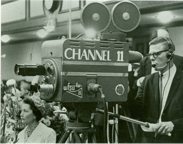 A man standing behind a film camera that says Channel 11